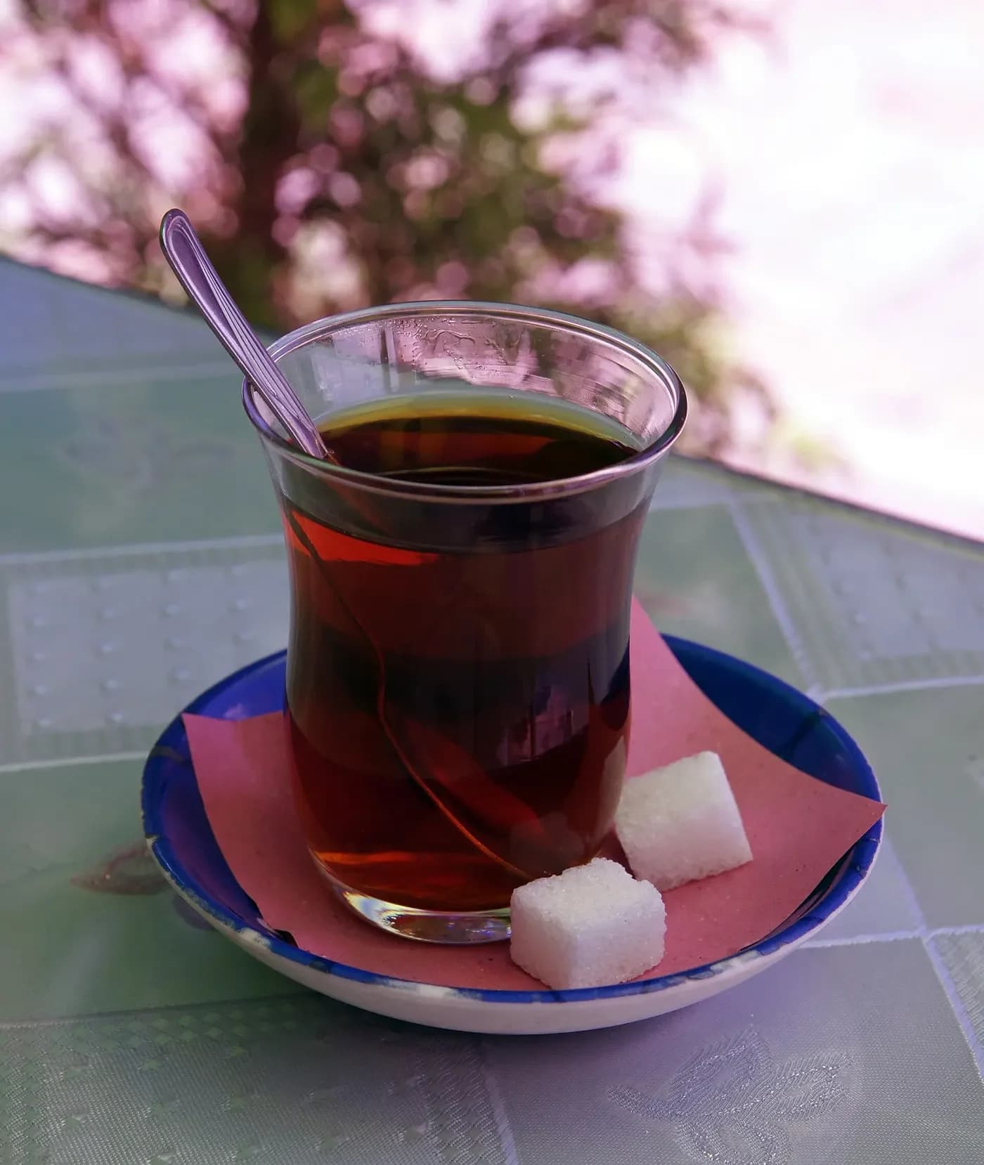 Tabakta şeker ve kaşıkla servis edilmiş ince belli bardakta çay